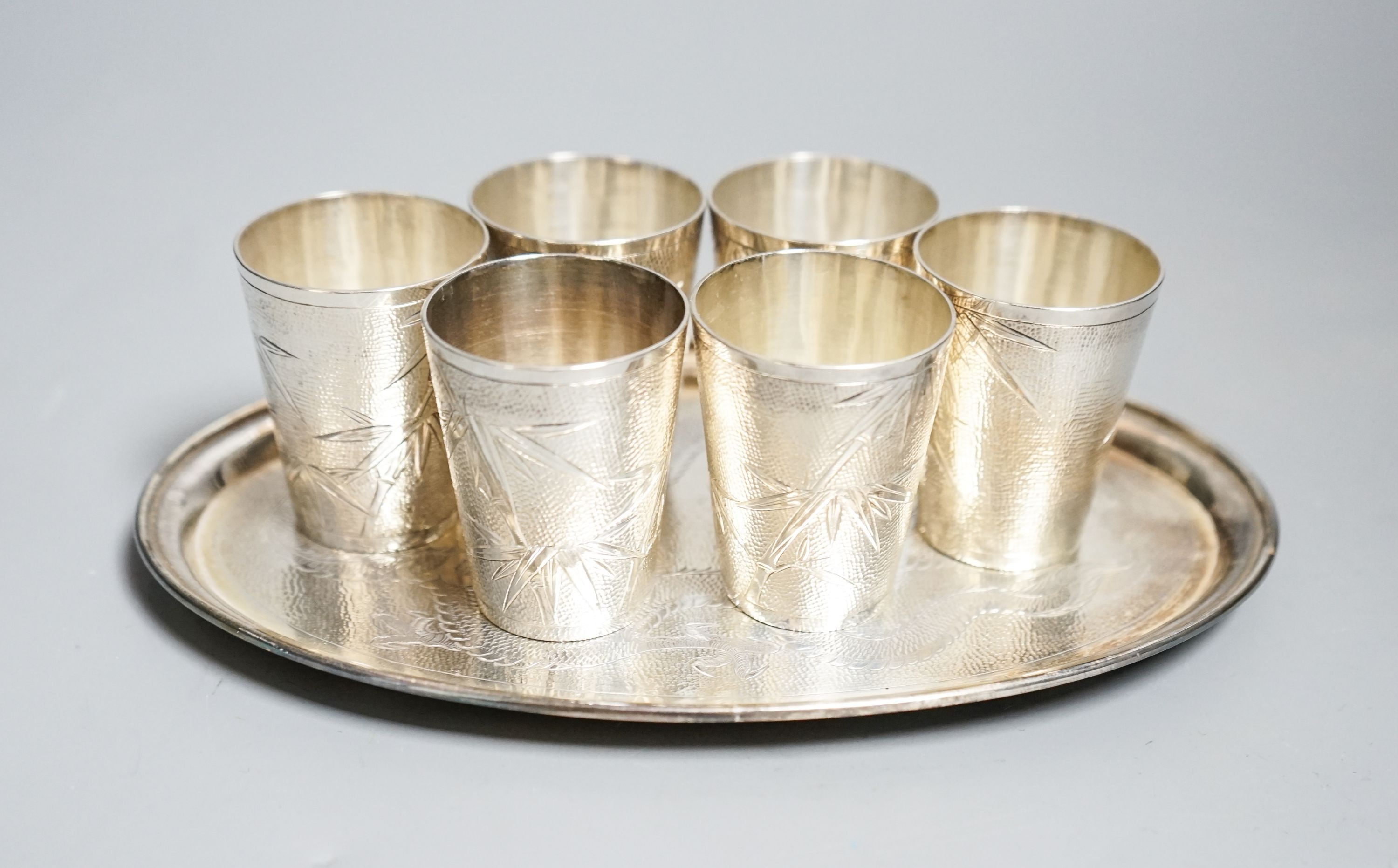 A set of six Chinese white metal tots by Tack Hing, 50mm and a small oval tray by Kingsburg, Hong Kong, 10.5oz.